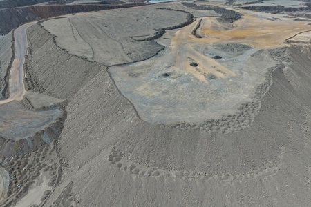 Aerial view of enormous mine waste dumps filled with benches