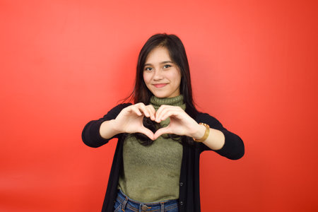 Showing Love Sign Of Beautiful Asian Woman Isolated On Red Backgroundの写真素材