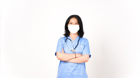 Young Asian female doctor using medical mask holding arms and looking at camera isolated on white backgroundの写真素材
