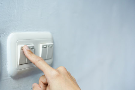 Woman pressing a light switch, energy saving concept