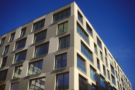 Looking up to an urban window front against blue skyの写真素材