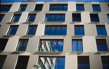 Looking up to an urban window front against blue skyの写真素材