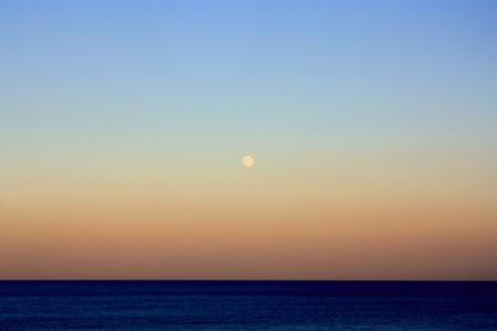 Romantic moon at sea. The moon above the horizon at susetの写真素材