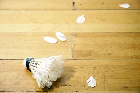 A smashed shuttlecock with its feather scattering on a badminton court.の写真素材