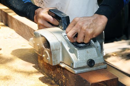 Closeup of a man working with a power belt wood sander.