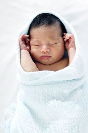 Portrait of a newborn baby sleeping peacefully, wrapped in blanket. の写真素材