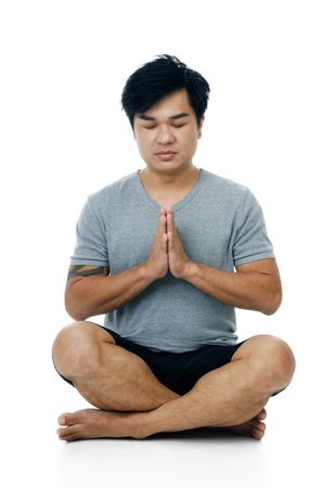 Portrait of a handsome young man in meditation pose on white background.の写真素材