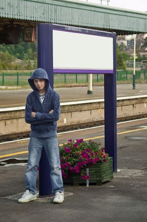 a Hoody or Thug leaning againts a sign post at a train station looking menacing の写真素材
