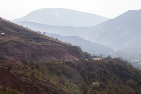 Foggy green hills and mountains with road and cars on closest hillの写真素材