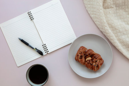 Top view of empty notepad with pen near cup of black coffee and pecan bun. Close upの写真素材