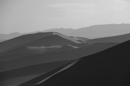 Walking alone on a sand ridge in the desert of Dunhuang, and the hazy silhouette of the desertの写真素材
