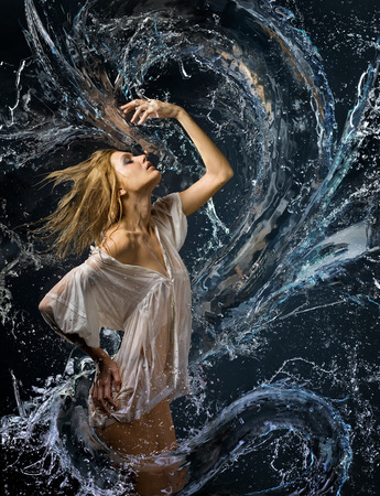 Aqua girl with wet shirt in a spray of water a liquid dragon before herの写真素材