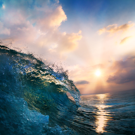pinky orange sunset on the beach at south summer coast and colorful blue surfing wave closingの写真素材