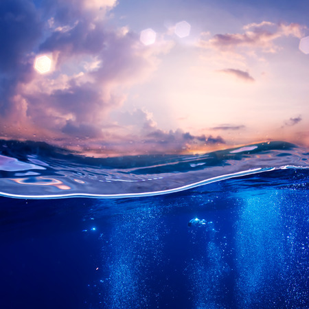 Tropical postcard sea water design template. Beautiful sunset at the sea nice pink clouds and blue water with air bubblesの写真素材