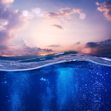 Tropical postcard sea water design template. Beautiful sunset at the sea nice pink clouds and blue water with air bubblesの写真素材