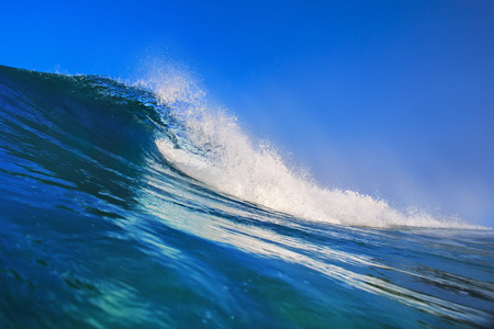 Shorebreak surfing tube wave. Pipeline in daylight with light of sun. Green Blue Ocean Water. Surfing template design with nobody. White splashes and ocean foam. Sky with no clouds. Surfing Rip Curl.の写真素材