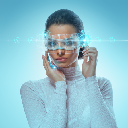 Image of Attractive Businesswoman Wearing Futuristic virtual Glasses Working With Holographic Hud Against Hightech backgroundの写真素材