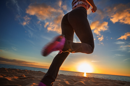 Running girl jogging at beachside at sunset time. Motion blurred imageの写真素材