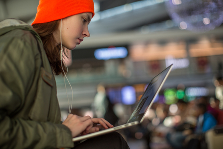 A girl working with laptop in waiting space in an airportの写真素材