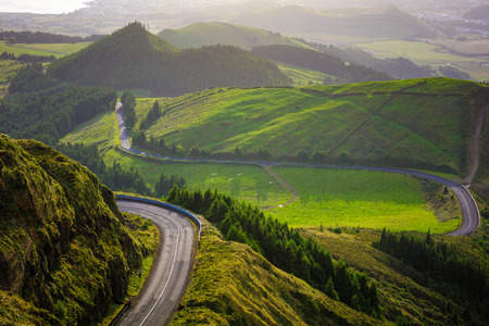 Aireview of green valley with drive between hills at sunset timeの写真素材