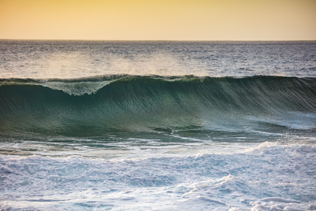 Sunset wave rising in ocean front view. Tropical seascape background with orange green tone for design templateの写真素材