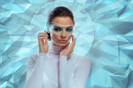 An attractive brunette model in futuristic office with virtual holographic glassesの写真素材