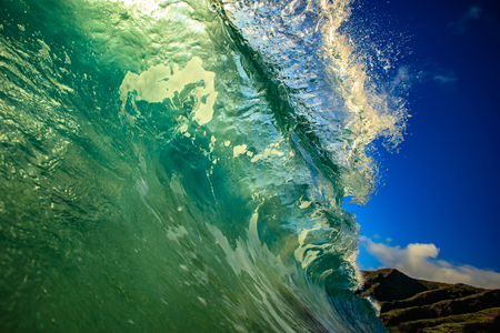 Giant bright clear ocean wave barreled and crashing against shoreの写真素材