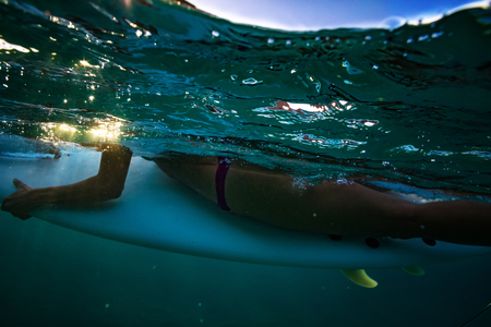 Surfer girl holding surfboard. Underwater view of water sport activityの写真素材