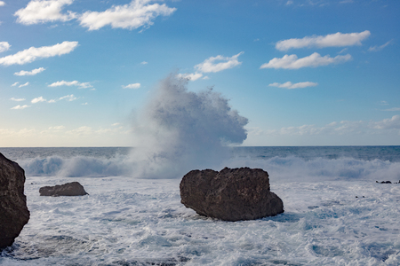 Big huge Shorebreak ocean splashes waves crushing shore with black rock on itの写真素材