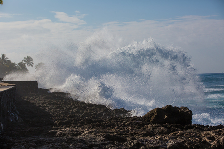 Tropical beach break, ocean wave crushing stone coastline, water splashesの写真素材