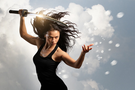 Beautiful Brunette with katana sword in spring floral environmentの写真素材