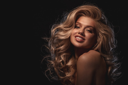 Beauty headshot of smiling fashion blonde model on dark flat backgroundの写真素材