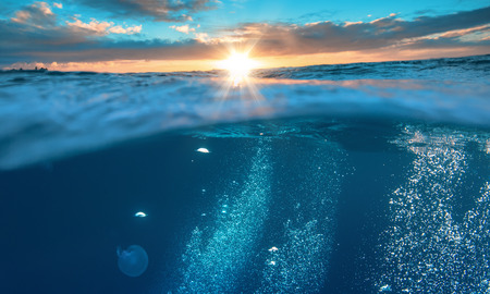 Water background, beautiful tropical sea, underwater view with sunset on skylineの写真素材