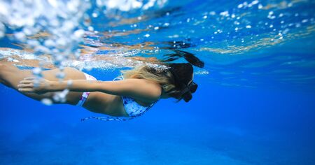 Fit sporty body girl swimming in sea observing coral bottom and reef in blue ocean water
の写真素材