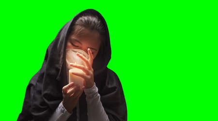 Mourning woman wearing black cloth holding candle with fire, the expression of deep sorrow for someone who has died during pandemicの写真素材