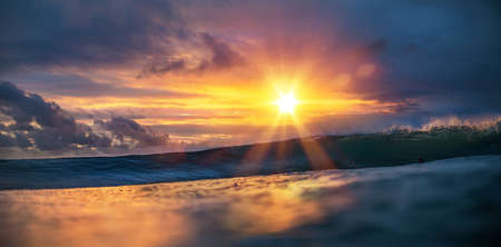 Sunset sea tropical background, surfing wave incoming with surfers on ocean water surfaceの写真素材