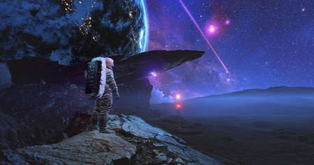 An astronaut in space suit standing on alien rocky planet under stars on the sky communicating with drone butterflyの写真素材