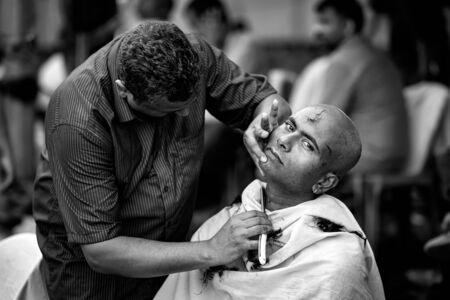 Close-up of men devotee getting tonsured or head shaving ritual in Thaipusam Festival.のeditorial素材