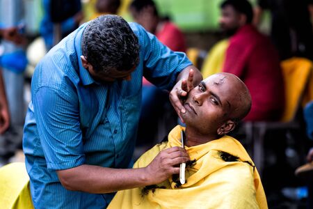Close-up of men devotee getting tonsured or head shaving ritual in Thaipusam Festival.のeditorial素材