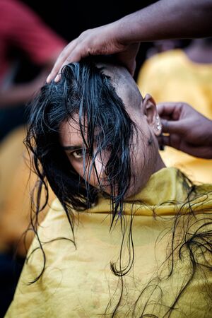 Close-up of young lady devotee getting tonsured or head shaving ritual in Thaipusam Festival.のeditorial素材