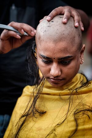 Close-up of young lady devotee getting tonsured or head shaving ritual in Thaipusam Festival.のeditorial素材