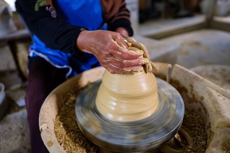 Closeup of Local woman demonstrates on making traditional clay jar called Labu Sayong or Essence Jar of Sayong inside workshop in Kuala Kangsar, Perak, Malaysia. Traditional Pottery concept.の写真素材