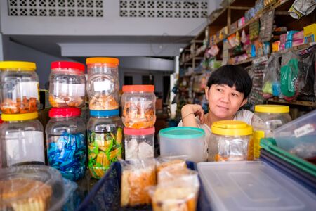 Asian Indonesian women in front of small local family-owned business store, locally called warung. Location is in Tasikmalaya, Indonesia. Selective Focus.