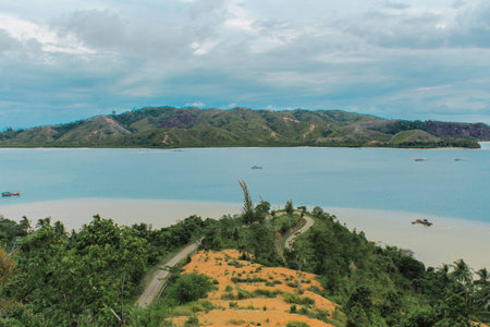 Scenic Curved Road on a Tropical Peninsula Overlooking Calm Blue Sea and Hills Across the Bayの写真素材