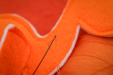 orange thread threaded on needleの写真素材