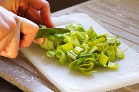Slicing leek in the kitchen with a small knifeの写真素材