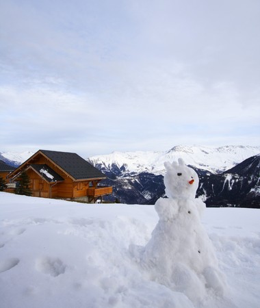 Snowman and chalet in winterの写真素材