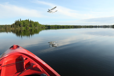 A calm morning takeoff with a Cessna caravan and a red kayak in the foregroundのeditorial素材