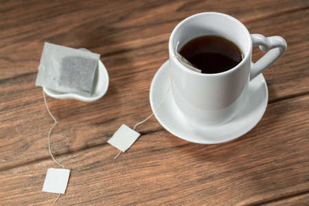 A cup of hot tea with a tea bag for boiling wooden backgroundの写真素材