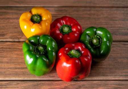 six large bell peppers different colors on a wooden boardの写真素材
